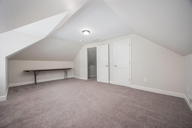 additional living space featuring vaulted ceiling and carpet flooring