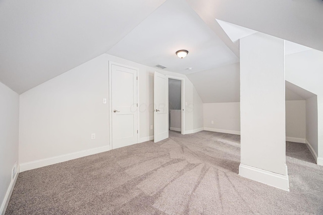 additional living space featuring vaulted ceiling and light carpet