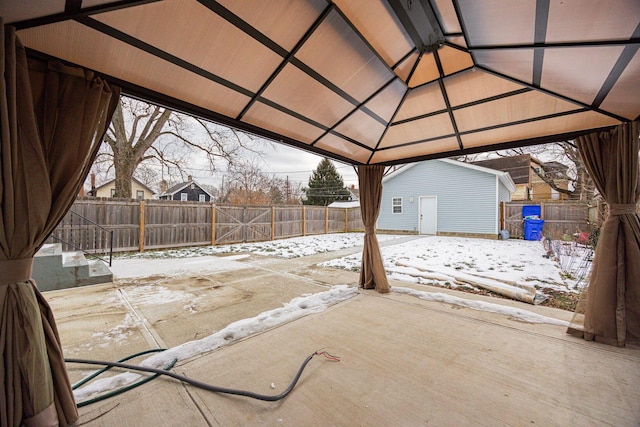 snow covered patio with a gazebo and an outbuilding