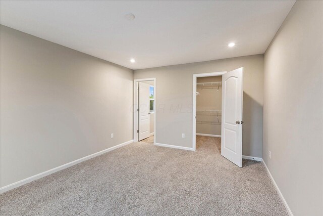 1221 Heathgate Way, Fairborn, OH 45324 - unfurnished bedroom with a walk in closet, light colored carpet, baseboards, recessed lighting, and a closet