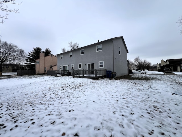 snow covered back of property with a deck