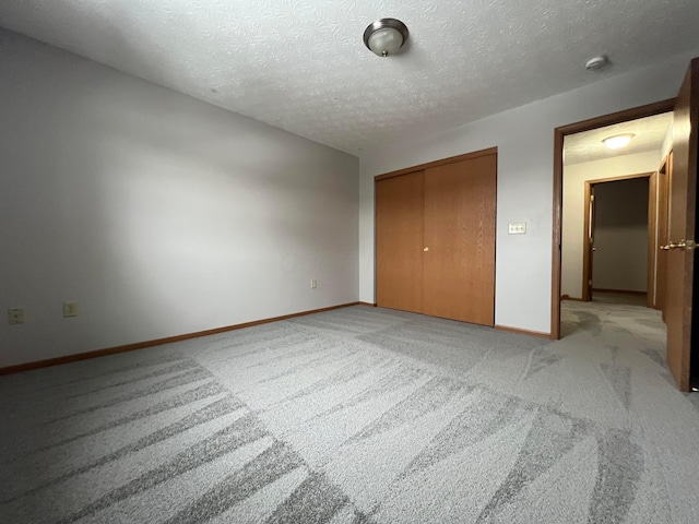 unfurnished bedroom featuring light carpet, a closet, and a textured ceiling