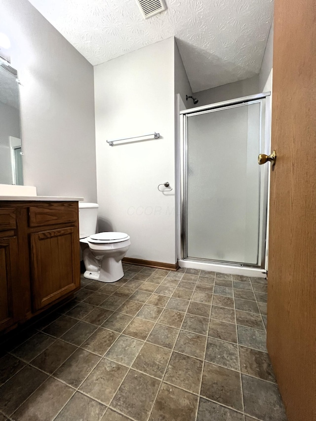 bathroom with vanity, a shower with shower door, toilet, and a textured ceiling