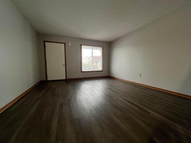 empty room featuring dark wood-type flooring and a textured ceiling