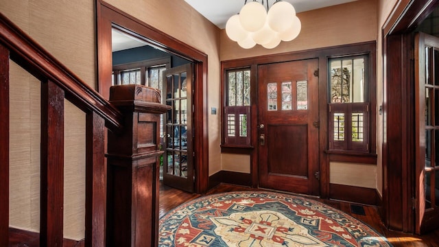 foyer entrance with baseboards, a notable chandelier, and wood finished floors