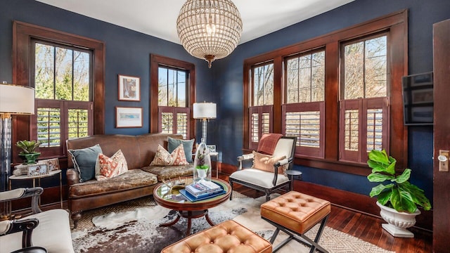 living area with a wealth of natural light, a notable chandelier, and wood finished floors