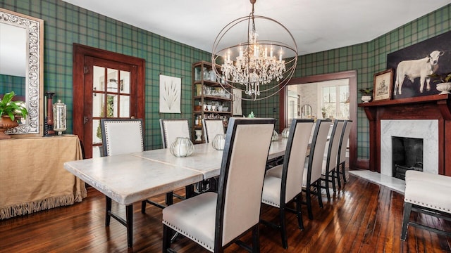 dining area with a chandelier, a fireplace, wallpapered walls, and wood-type flooring