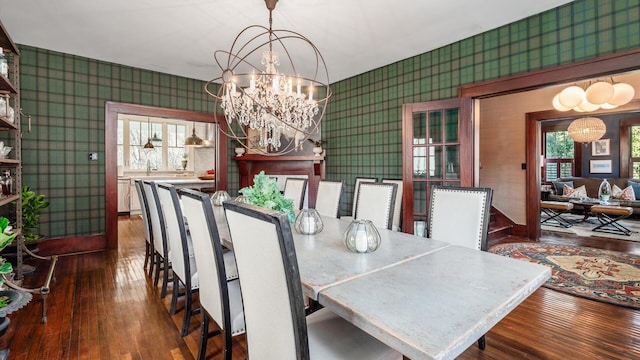 dining room with hardwood / wood-style flooring, an inviting chandelier, and wallpapered walls