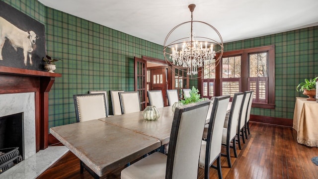 dining area with a premium fireplace, hardwood / wood-style flooring, a notable chandelier, and wallpapered walls