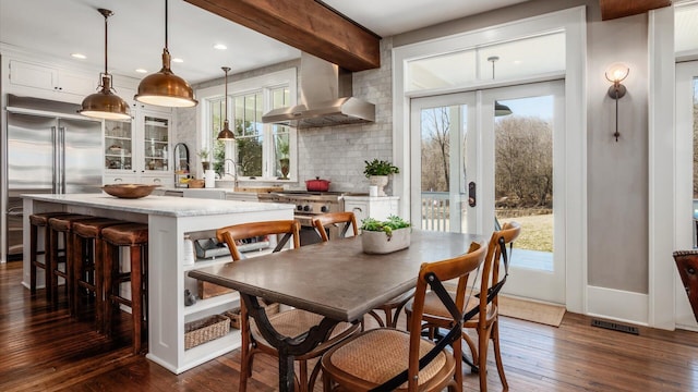 kitchen featuring visible vents, stainless steel built in fridge, range, wall chimney exhaust hood, and dark wood-style flooring