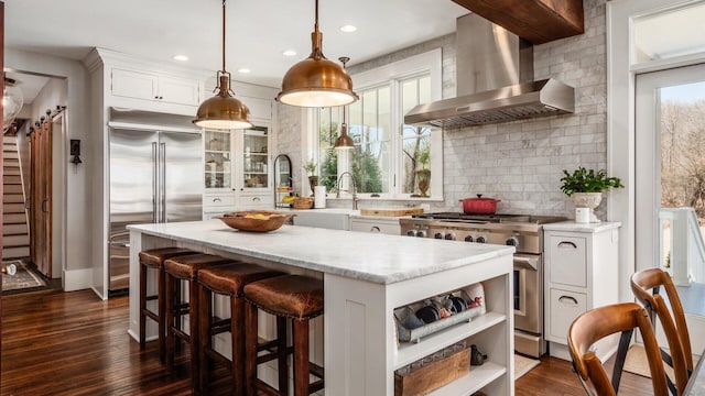 kitchen featuring high quality appliances, open shelves, dark wood-type flooring, wall chimney exhaust hood, and a center island