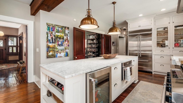 kitchen featuring dark wood-type flooring, beverage cooler, appliances with stainless steel finishes, and a center island