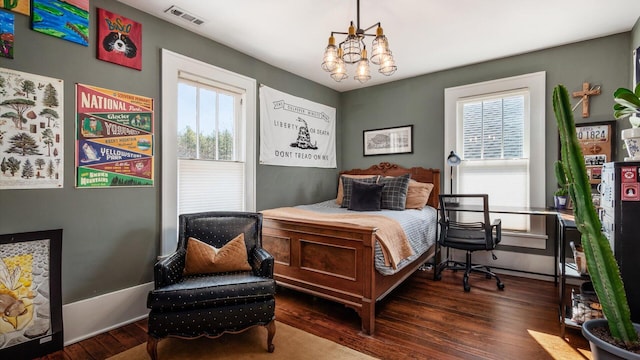 bedroom featuring visible vents, multiple windows, wood finished floors, and a chandelier