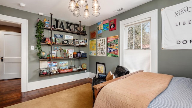 bedroom featuring visible vents, baseboards, a notable chandelier, and wood finished floors