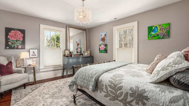 bedroom featuring visible vents, baseboards, wood finished floors, and a chandelier