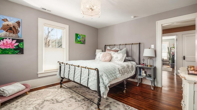 bedroom with visible vents, baseboards, wood finished floors, and a chandelier