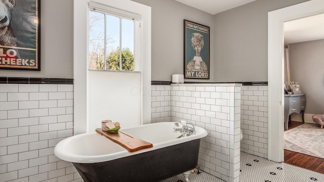 full bathroom with wainscoting, a freestanding bath, tile walls, and a sink