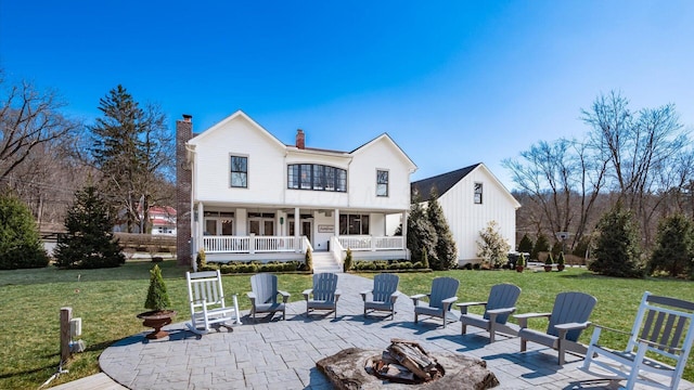 rear view of house with a patio, a porch, a fire pit, and a lawn