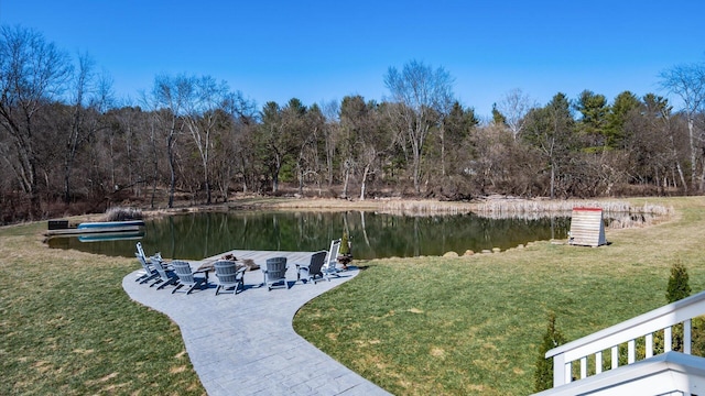 dock area with a view of trees, a water view, a lawn, and a fire pit