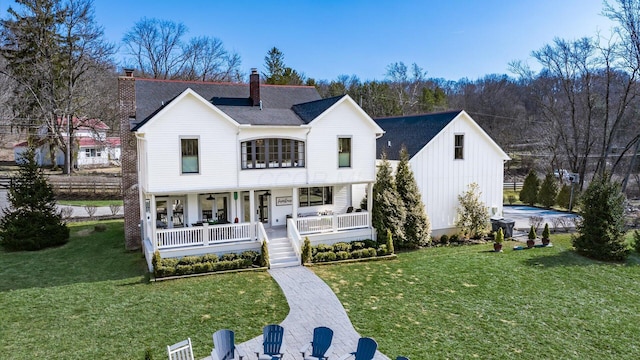 view of front of property with covered porch, board and batten siding, a chimney, and a front lawn