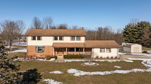 view of property featuring a yard, covered porch, and a storage unit