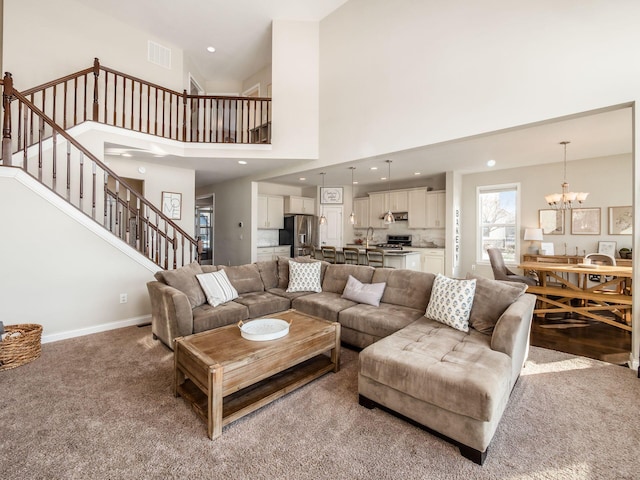 carpeted living room with a chandelier and a high ceiling