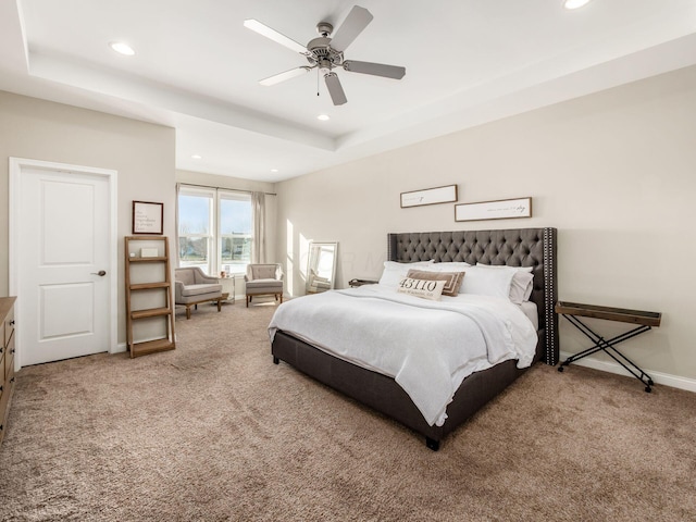 bedroom with a raised ceiling, carpet floors, and ceiling fan