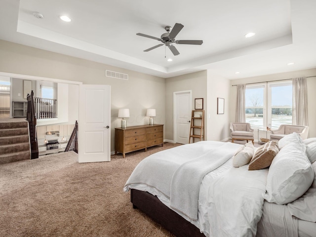 carpeted bedroom featuring a water view, ceiling fan, and a raised ceiling