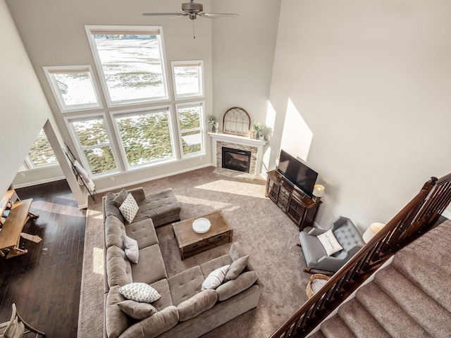 living room with wood-type flooring, a towering ceiling, and ceiling fan