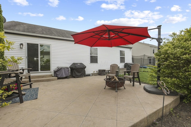 view of patio featuring a grill, an outdoor fire pit, and a trampoline