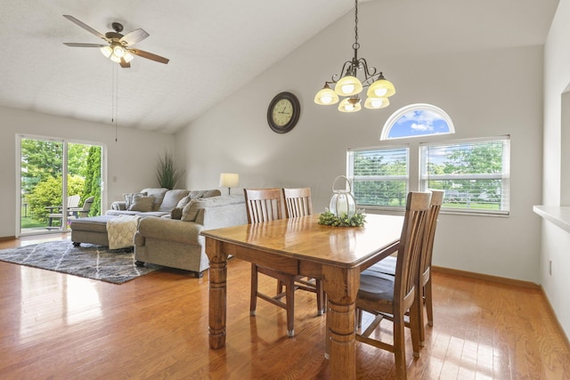 dining room featuring high vaulted ceiling, ceiling fan with notable chandelier, and light hardwood / wood-style floors