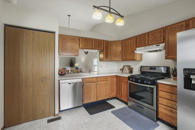 kitchen with appliances with stainless steel finishes, lofted ceiling, sink, hanging light fixtures, and a textured ceiling