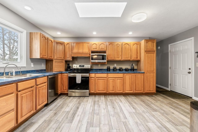 kitchen with stainless steel appliances, dark countertops, premium range hood, and a sink