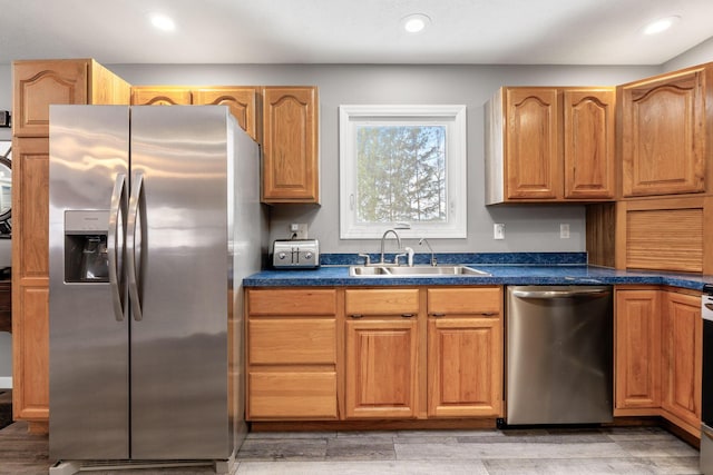 kitchen featuring appliances with stainless steel finishes, dark countertops, a sink, and recessed lighting