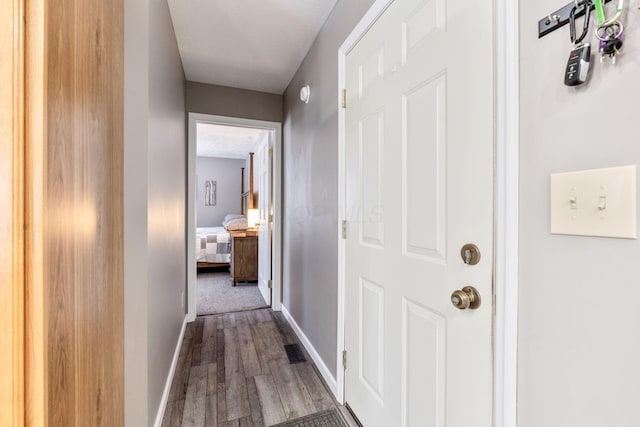 hallway with visible vents, baseboards, and wood finished floors