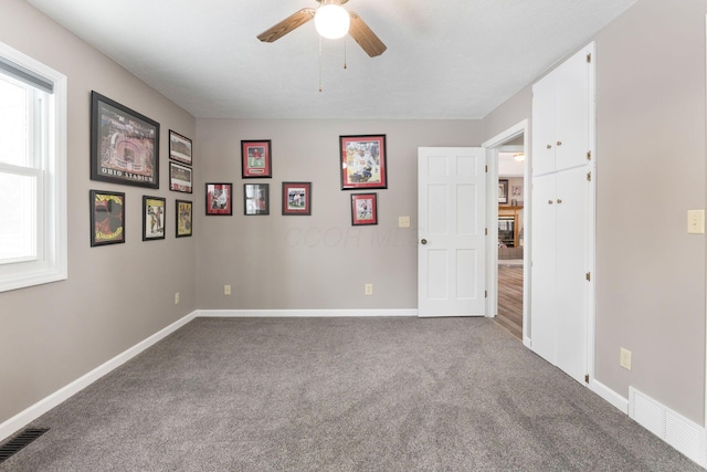 spare room with carpet, visible vents, and baseboards