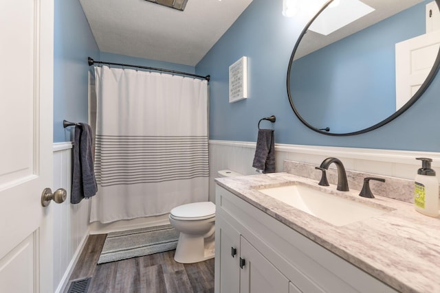 full bathroom featuring a wainscoted wall, visible vents, toilet, vanity, and wood finished floors