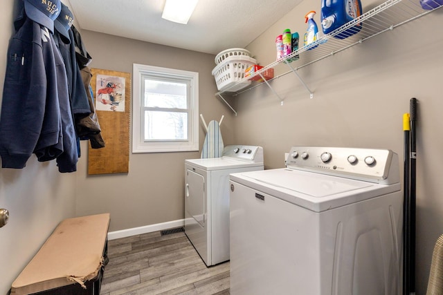 laundry area with light wood-style floors, laundry area, baseboards, and washing machine and clothes dryer