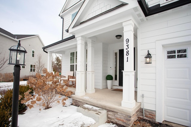 snow covered property entrance with covered porch