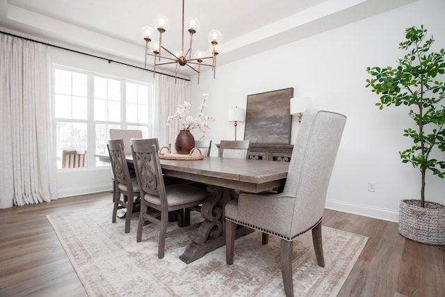 dining area with hardwood / wood-style floors and an inviting chandelier