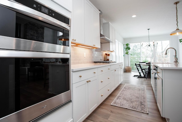 kitchen featuring hanging light fixtures, backsplash, white cabinets, and appliances with stainless steel finishes