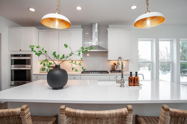 kitchen with appliances with stainless steel finishes, pendant lighting, wall chimney range hood, and backsplash