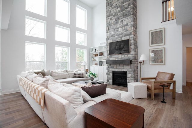 living room featuring light wood-type flooring, a fireplace, and a high ceiling