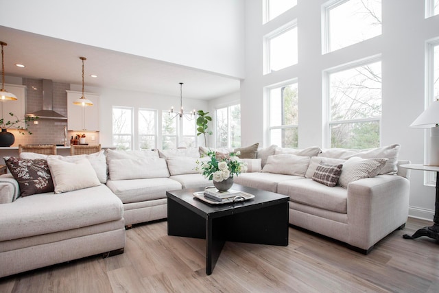 living room featuring a towering ceiling, a chandelier, and light hardwood / wood-style floors