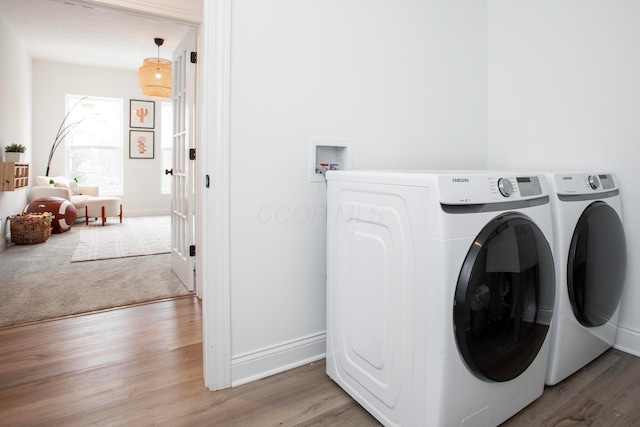 clothes washing area featuring washing machine and clothes dryer and light hardwood / wood-style floors