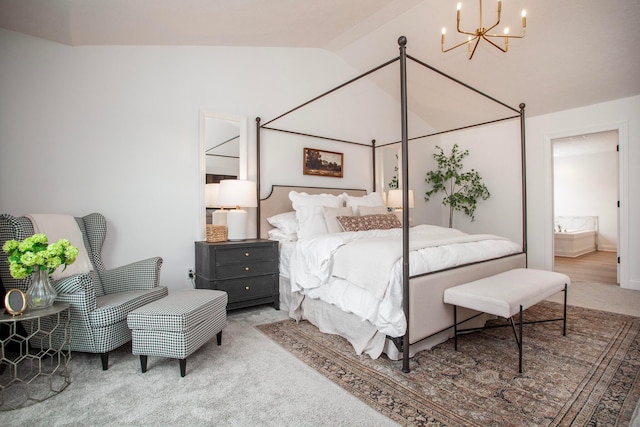 carpeted bedroom with ensuite bathroom, vaulted ceiling, and an inviting chandelier