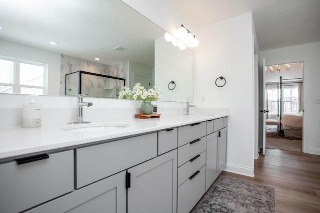 bathroom featuring hardwood / wood-style flooring, vanity, a shower with door, and a notable chandelier