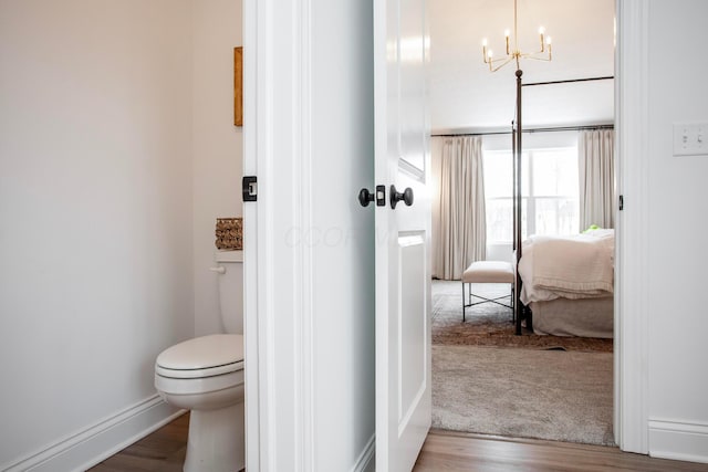 bathroom featuring hardwood / wood-style flooring, a chandelier, and toilet