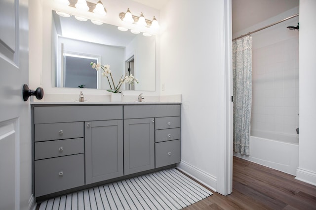 bathroom with hardwood / wood-style flooring, vanity, and shower / bathtub combination with curtain