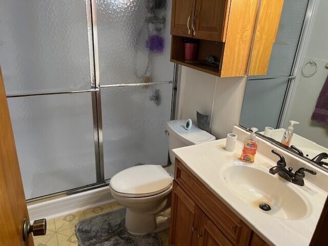 bathroom with vanity, a shower with door, and toilet